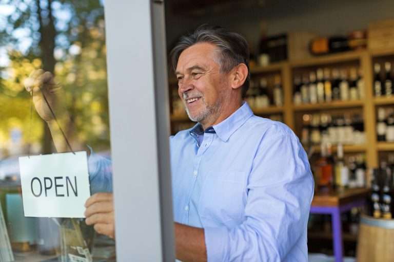 Wine shop owner holding open sign